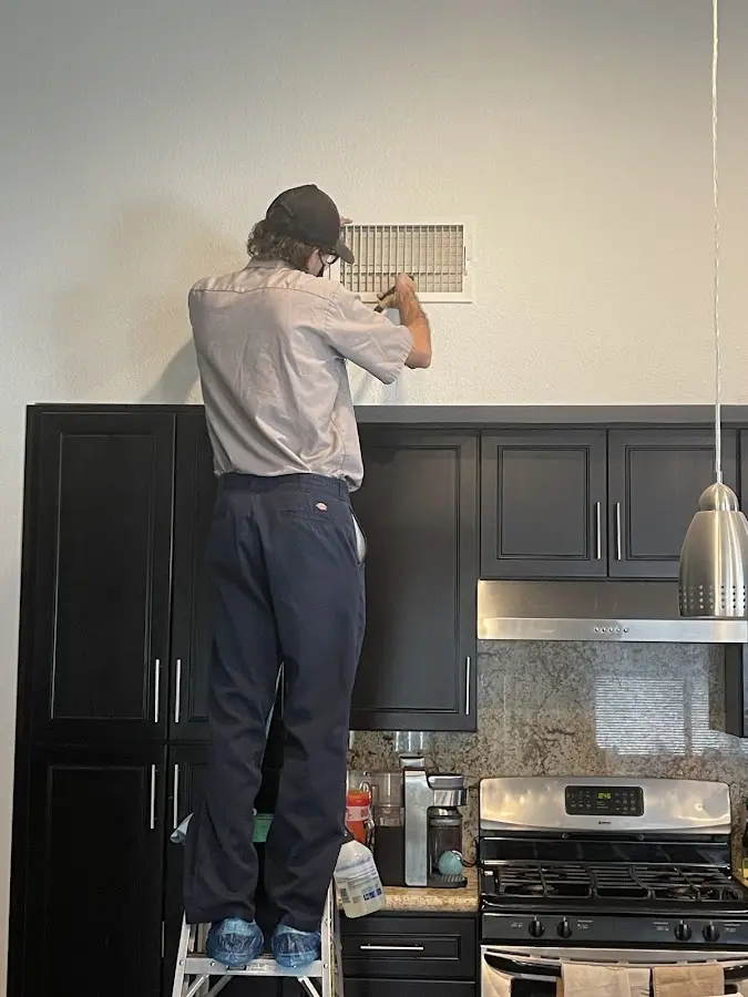 Technician inspecting an air vent during HVAC service in Adairsville